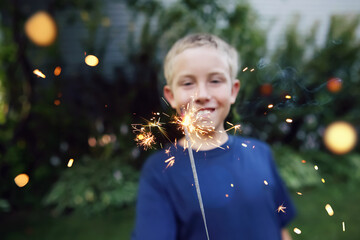 Smiling boy holding sparklers. Focus on sparkler