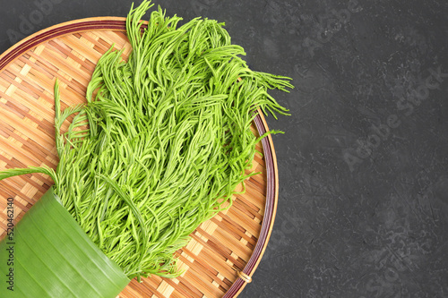 Acacia pennata ,Climbing wattle or Cha-om green leaves on bamboo colander. empty space for text. herbal vegetable and cooking concept. photo