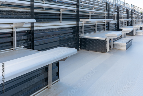 Empty metal outdoor stadium accessible bleacher seats with companion seats at front aisle.

