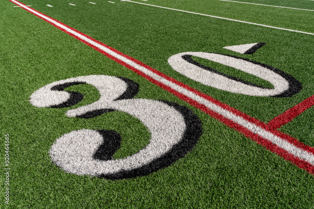 Synthetic turf slanted football 30 yard line in white with black number shadow along with red lacrosse line and yellow soccer mid field line Synthetic turf slanted football 30 yard line in white with black number shadow along with red lacrosse line and yellow soccer mid field line
