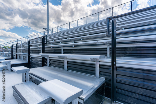 Empty metal outdoor stadium accessible bleacher seats with companion seats at front aisle. 