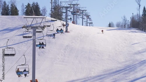 Slow motion shot of a ski resorts gondolas, next to downhill skier skis down photo