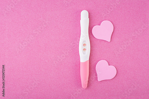 Positive pregnancy test with hearts isolated on pink background