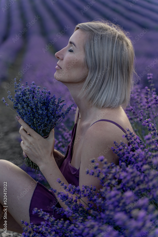 A middle-aged woman sits in a lavender field and enjoys aromatherapy. Aromatherapy concept, lavender oil, photo session in lavender A middle-aged woman sits in a lavender field and enjoys aromatherapy. Aromatherapy concept, lavender oil, photo session in lavender