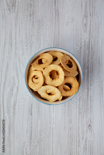 Homemade apple chips in a bowl on a white wooden background, top view. Flat lay, overhead, from above.