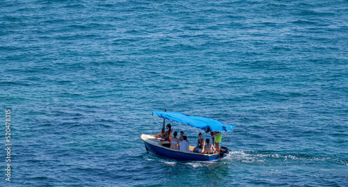 Isolated small motor boat with tourists on the shore of Budva beach © Oren