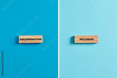 The words discrimination and inclusion on wooden blocks. Dilemma or choice between discrimination or inclusion photo