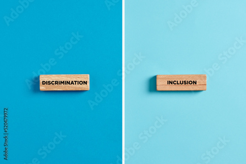 The words discrimination and inclusion on wooden blocks. Dilemma or choice between discrimination or inclusion