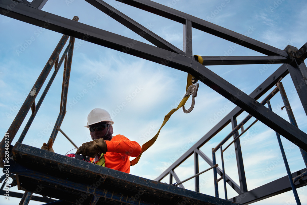 A Worker are working on the structure of the building with Fall arrestor device for worker with hooks for safety body harness at construction site.