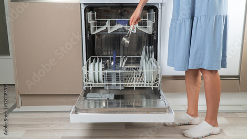 A woman puts cutlery in a dishwasher