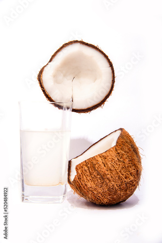 Coconut in two half and small pieces of coconut coconut oil and coconut water in a glass selective focus