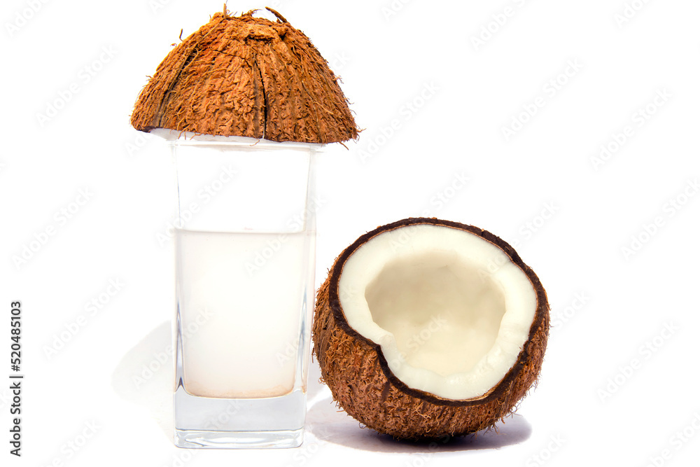 Coconut in two half and small pieces of coconut coconut oil and coconut water in a glass selective focus Coconut in two half and small pieces of coconut coconut oil and coconut water in a glass selective focus