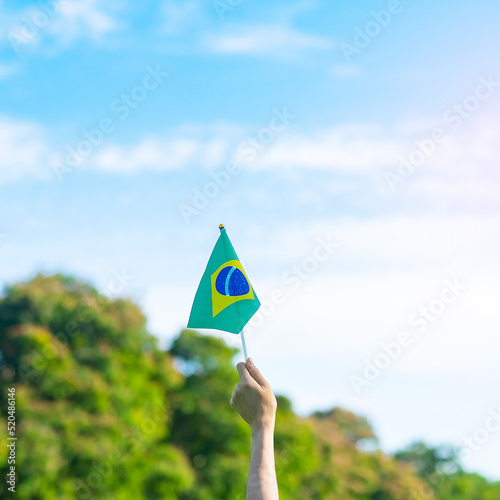 hand holding Brazil flag on blue sky background. September Independence day and Happy celebration concepts