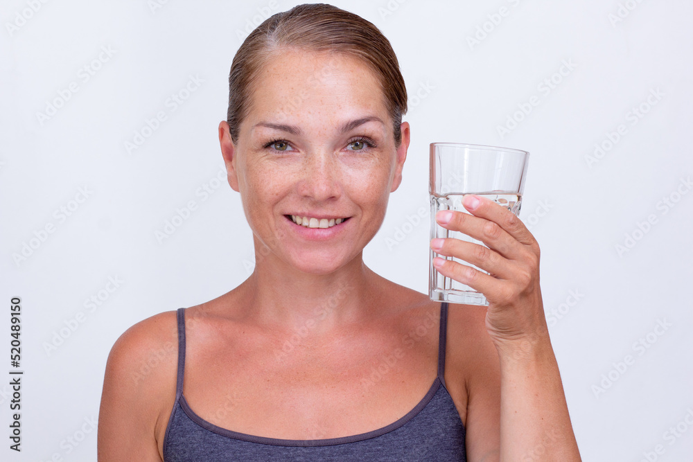 Caucasian beautiful middle aged woman of 40s holding glass of pure water on white background looking at camera Caucasian beautiful middle aged woman of 40s holding glass of pure water on white background looking at camera