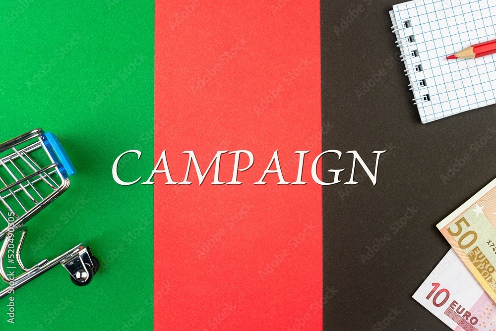 CAMPAIGN - word (text) and euro money on a table of different colors, a trolley, a basket of grocery notepad and a red pencil. Business concept, buying, selling, supermarket, store (copy space).