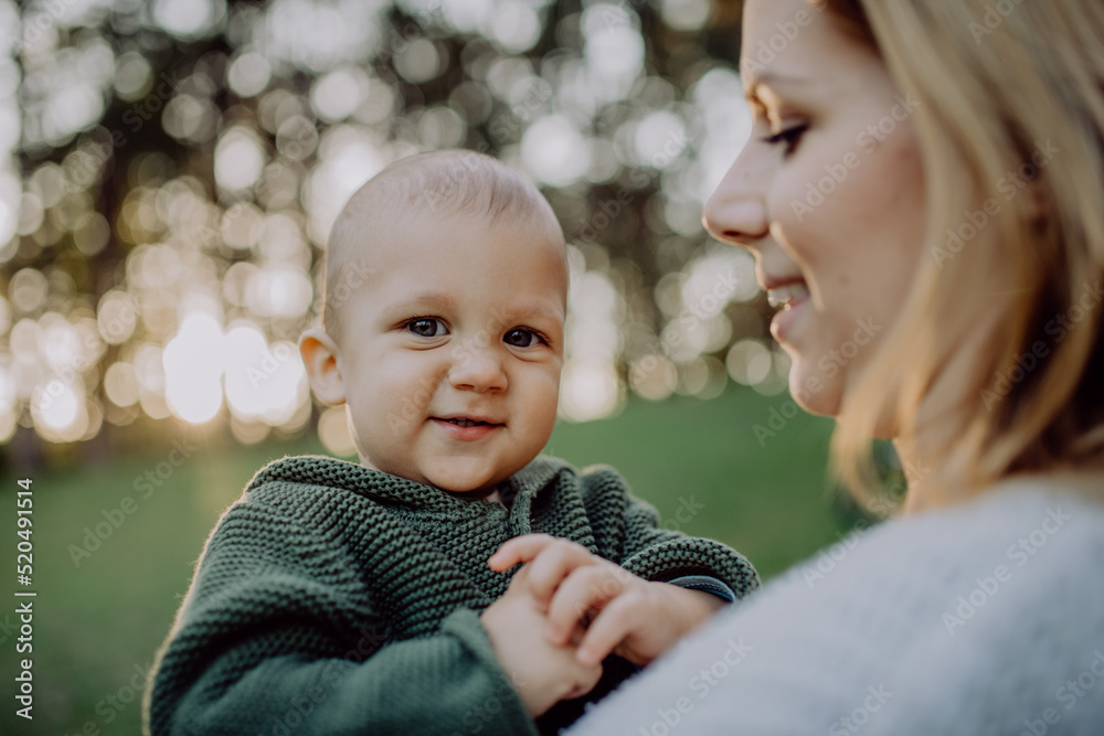 Obraz premium Mother holding her little baby son wearing knitted sweater during walk in nature, close-up