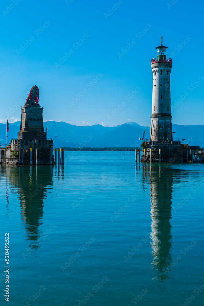 Germany, Lindau city port lighthouse and beautiful view to austria and bregenz alsp mountains reflecting in silent bodensee lake water