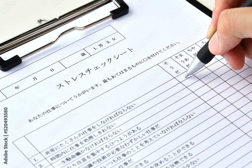 ストレスチェックシートに記入するビジネスマンの手元 ストレスチェックシートに記入するビジネスマンの手元