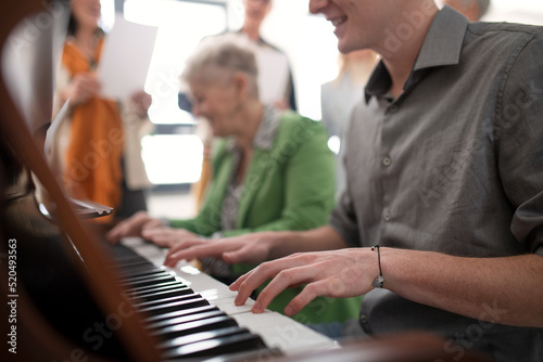 Valokuva Senior woman with young teacher playing at piano in choir rehearsal