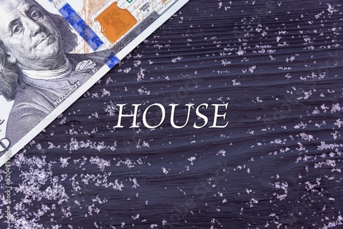 HOUSE - word (text) on a dark wooden background, money, dollars and snow. Business concept (copy space).