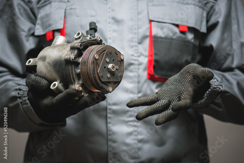 Auto mechanic showing a broken air conditioning compressor close up. photo