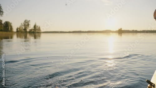 Unknown person sails on kayak using yellow paddle on forest lake. Droplets fall into clear water at sunset. Anonymous makes waves with paddle closeup photo