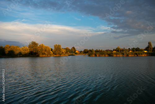 Palic Lake, Serbia, just before sunset on the beautiful day in the  beginning of the autumn with lake cane and the house in the background and different types of clouds in the sky  