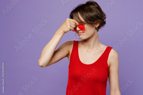 Young tired sick ill minded woman 20s she wear red tank shirt eyeglasses look camera keep eyes closed rub put hand on nose isolated on plain purple backround studio portrait. People lifestyle concept.