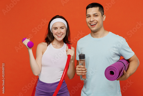 Canvastavla Young fitness trainer instructor sporty two man woman in headband t-shirt hold yoga mat hula hup bottle dumbbell spend weekend in home gym isolated on plain orange background