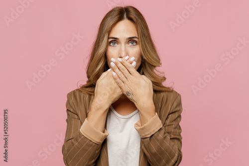 Young shocked surprised impressed scared sad employee business woman 30s she wearing casual brown classic jacket cover mouth with hand isolated on plain pastel light pink background studio portrait.