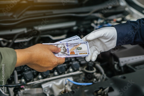 Mechanic man takes cash as payment from customer.after finish checking car system.Professional service.checking the opened hood car.Repair service.