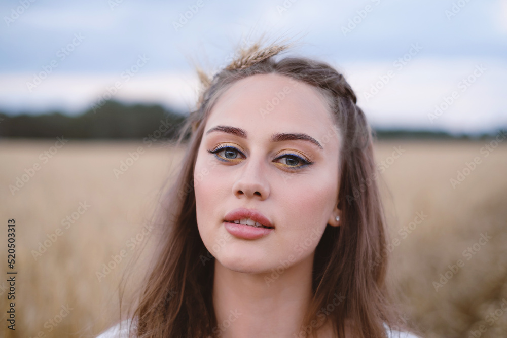 Beautiful woman on wheat field. Young female with makeup beauty portrait outdoors. Ukrainian agricultural land with rye. Boho chic style.