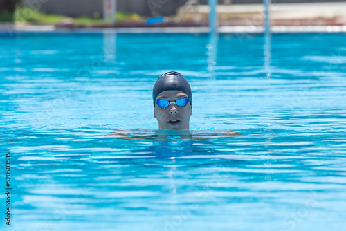 Portrait of a young man, athlete, teenager with swimming goggles in pool, relaxed, thoughtful. Close up.