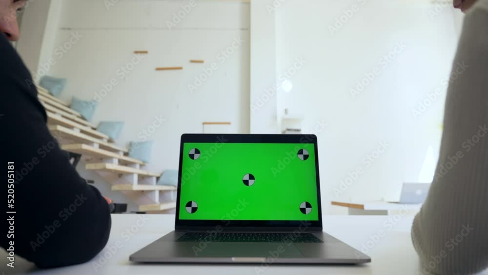 Men colleagues watch educational lessons on modern laptop sitting at desk in office. Open computer with chromakey screen closeup replace with Your content Men colleagues watch educational lessons on modern laptop sitting at desk in office. Open computer with chromakey screen closeup replace with Your content