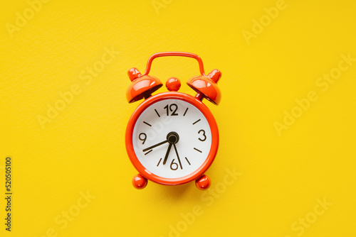 Red alarm clock on a yellow background. Close-up