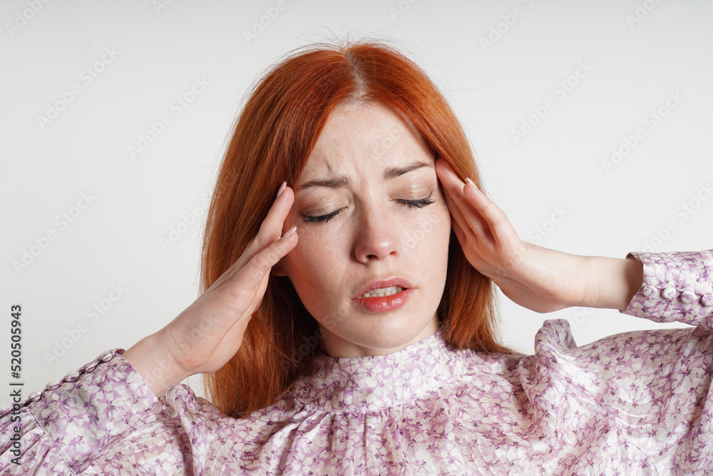 woman suffering from headache or migraine massaging her temples to relieve the pain woman suffering from headache or migraine massaging her temples to relieve the pain