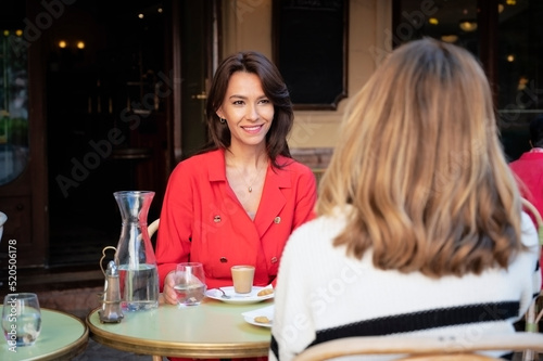 Two woman sitting together at outdoor cafe and chatting