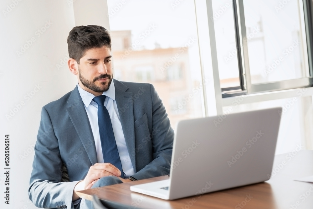 Shot of businessman using laptop while working at the office Shot of businessman using laptop while working at the office