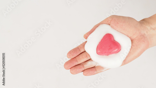 Hands with foaming soap and pink soap on white background. Studio shot