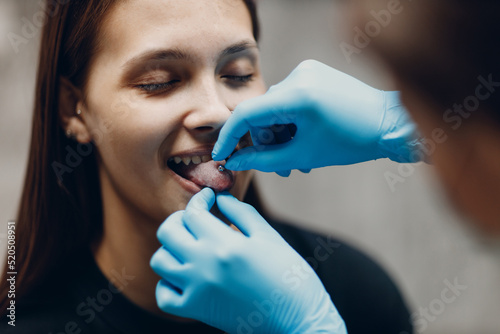 Young woman doing tonque piercing at beauty studio salon photo