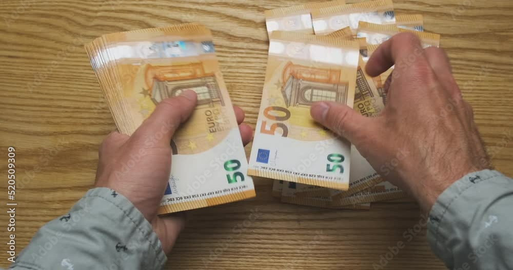 Man counts money. A bundle of banknotes of 50 euros in the hands, puts on the table when counting. The concept of taxes, winning the lottery, taxes, salary, microcredit, welfare Man counts money. A bundle of banknotes of 50 euros in the hands, puts on the table when counting. The concept of taxes, winning the lottery, taxes, salary, microcredit, welfare