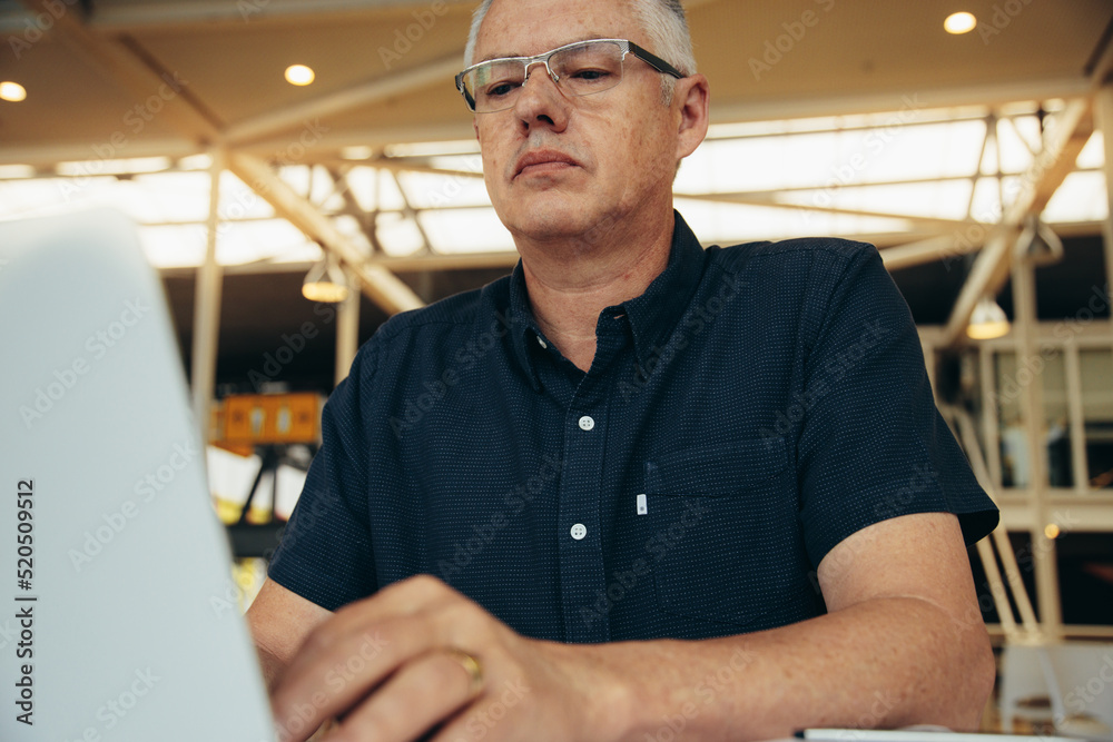 Serious male executive doing research on laptop in office Serious male executive doing research on laptop in office