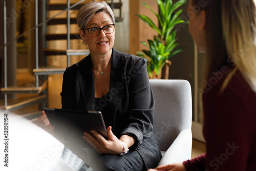 Businesswoman with tablet explaining to coworker in office