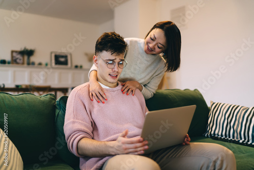 Asian woman hug caucasian man with laptop on sofa