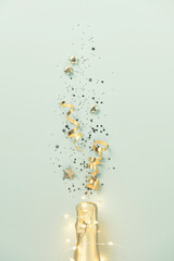 Champagne bottle with gold party streamers on blue background flat lay