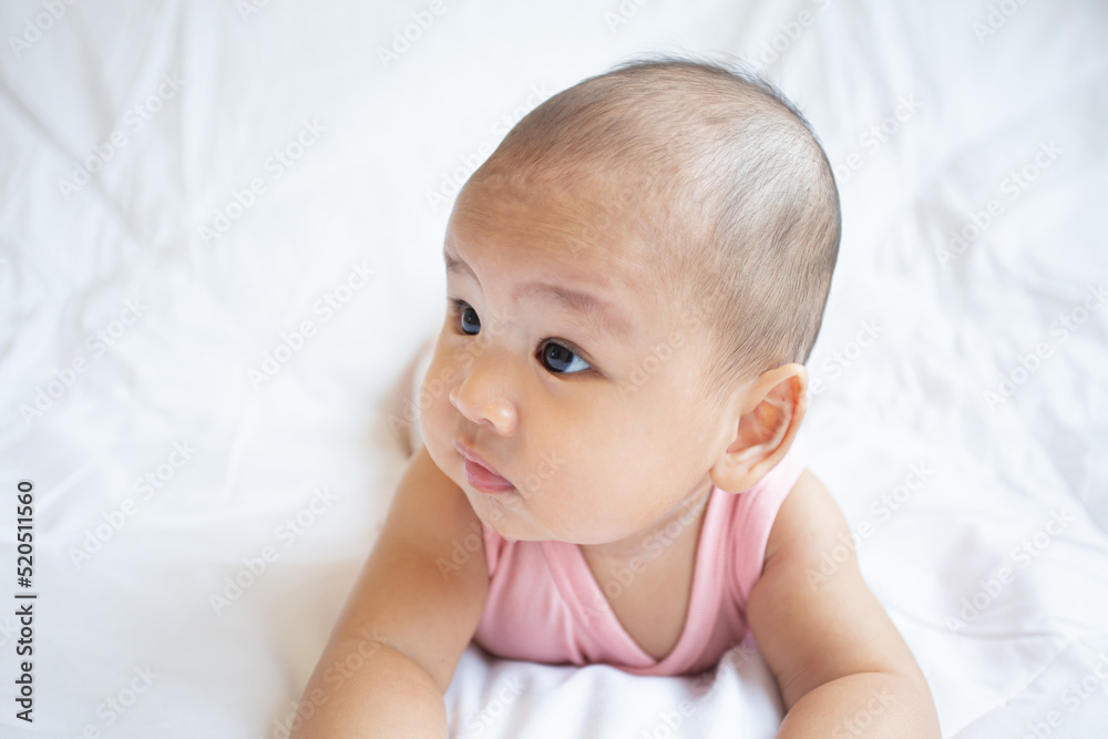 Asian cute baby in white sunny bedroom. Newborn child relaxing on bed Asian cute baby in white sunny bedroom. Newborn child relaxing on bed