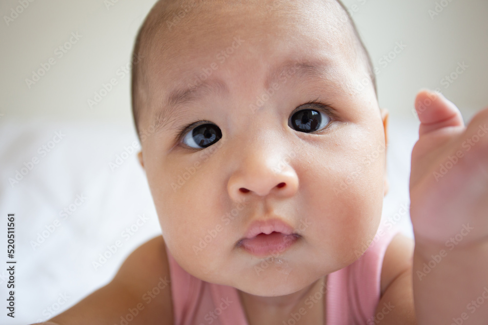 Asian cute baby in white sunny bedroom. Newborn child relaxing on bed Asian cute baby in white sunny bedroom. Newborn child relaxing on bed