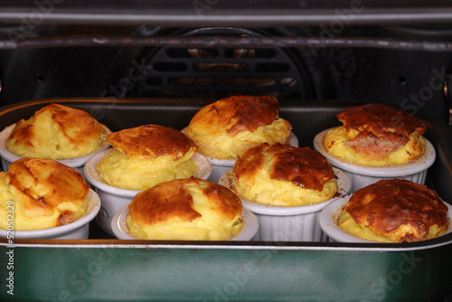  group of pecorino cheese souffle in a water bath in the oven