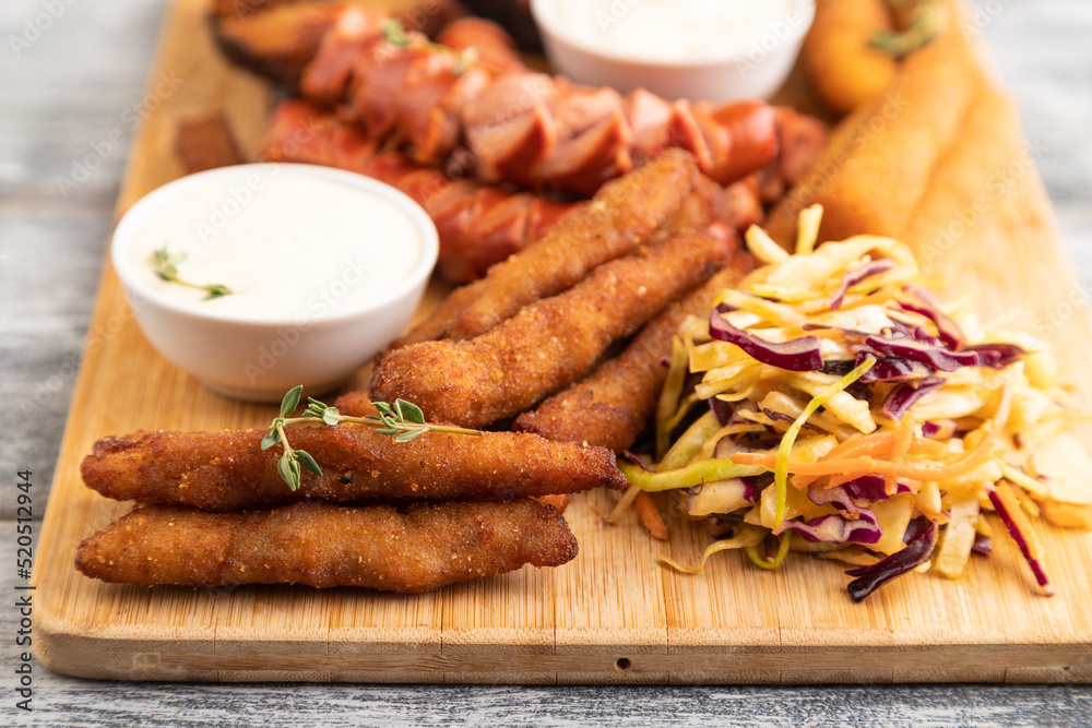 set of snacks: sausages, nuggets, cheese sticks, toast, cabbage salad. Side view, selective focus. set of snacks: sausages, nuggets, cheese sticks, toast, cabbage salad. Side view, selective focus.