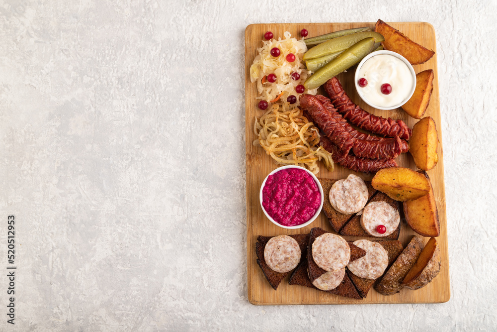 Fototapeta premium set of snacks: sausages, toast, sauerkraut, marinated onion and cucumber, baked potato. Top view, copy space.